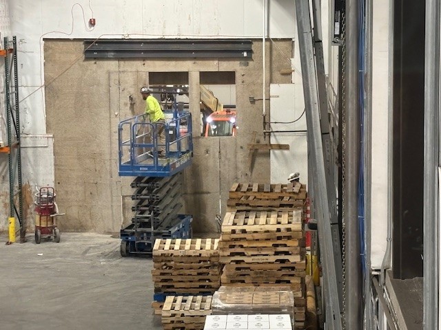 A construction worker in a scissor lift working on the wall cut preparation.