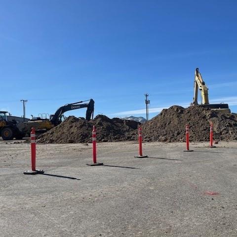 Liquor Warehouse Construction Site marked by orange traffic cones with two large excavators in the background.