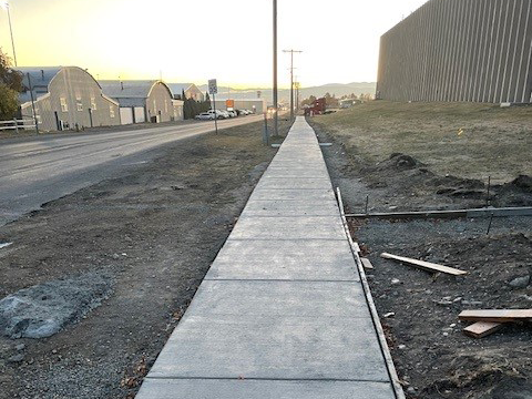 A newly poured concrete sidewalk along the road