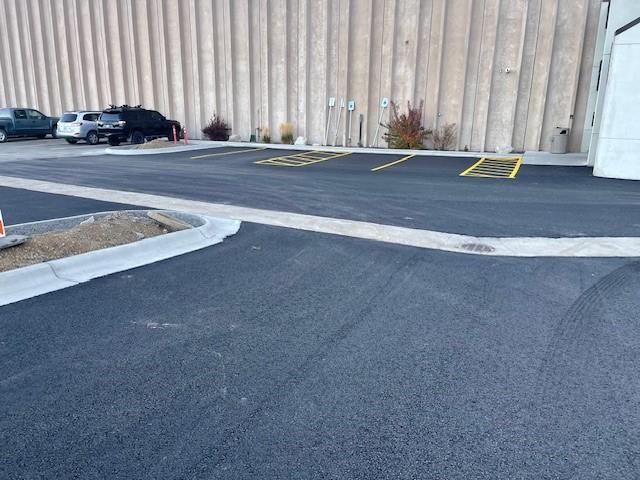 Freshly paved asphalt in a parking lot, with yellow-painted parking lines and newly installed curbs.