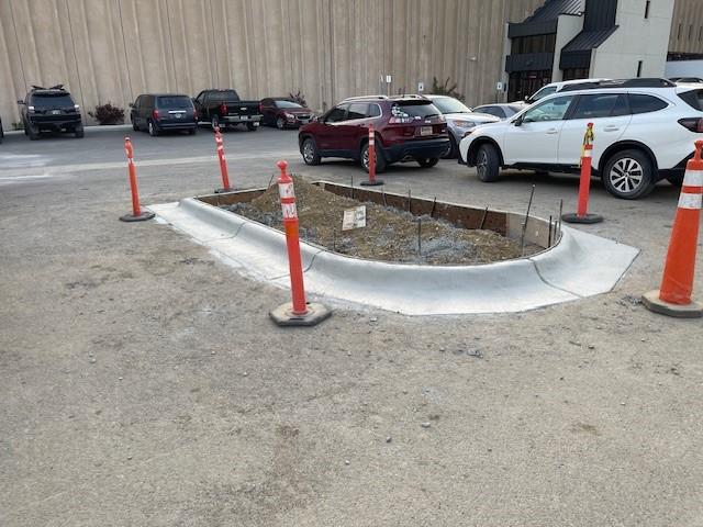 Curbed island with orange construction cones around it in a parking lot