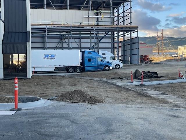 Construction site with trucks parked along the warehouse.