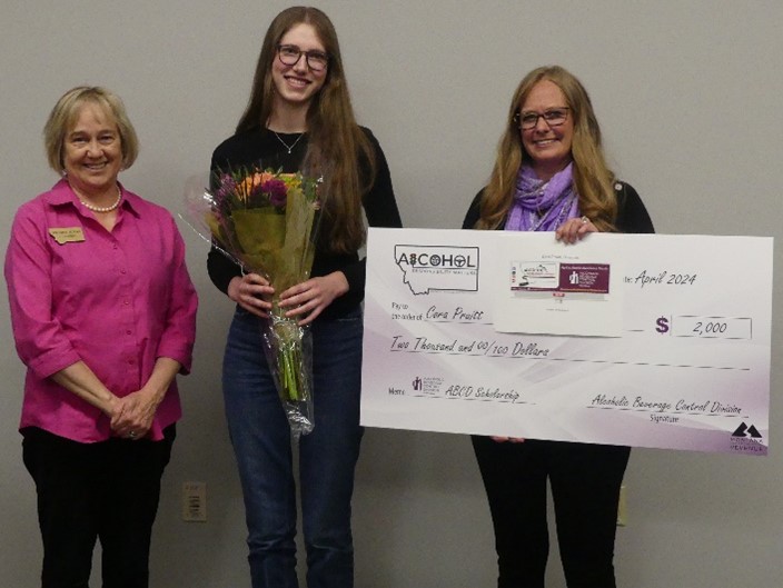 Scholarship winner Cora Pruitt with Kristen Juras and Becky Schlauch, holding a scholarship check and flowers at the award ceremony.